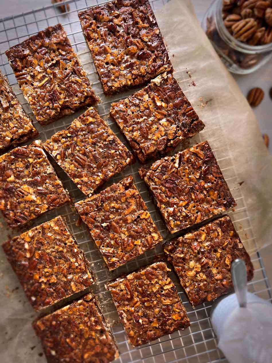 Caramel pecan bars with a gluten-free shortbread crust on a cooling rack.