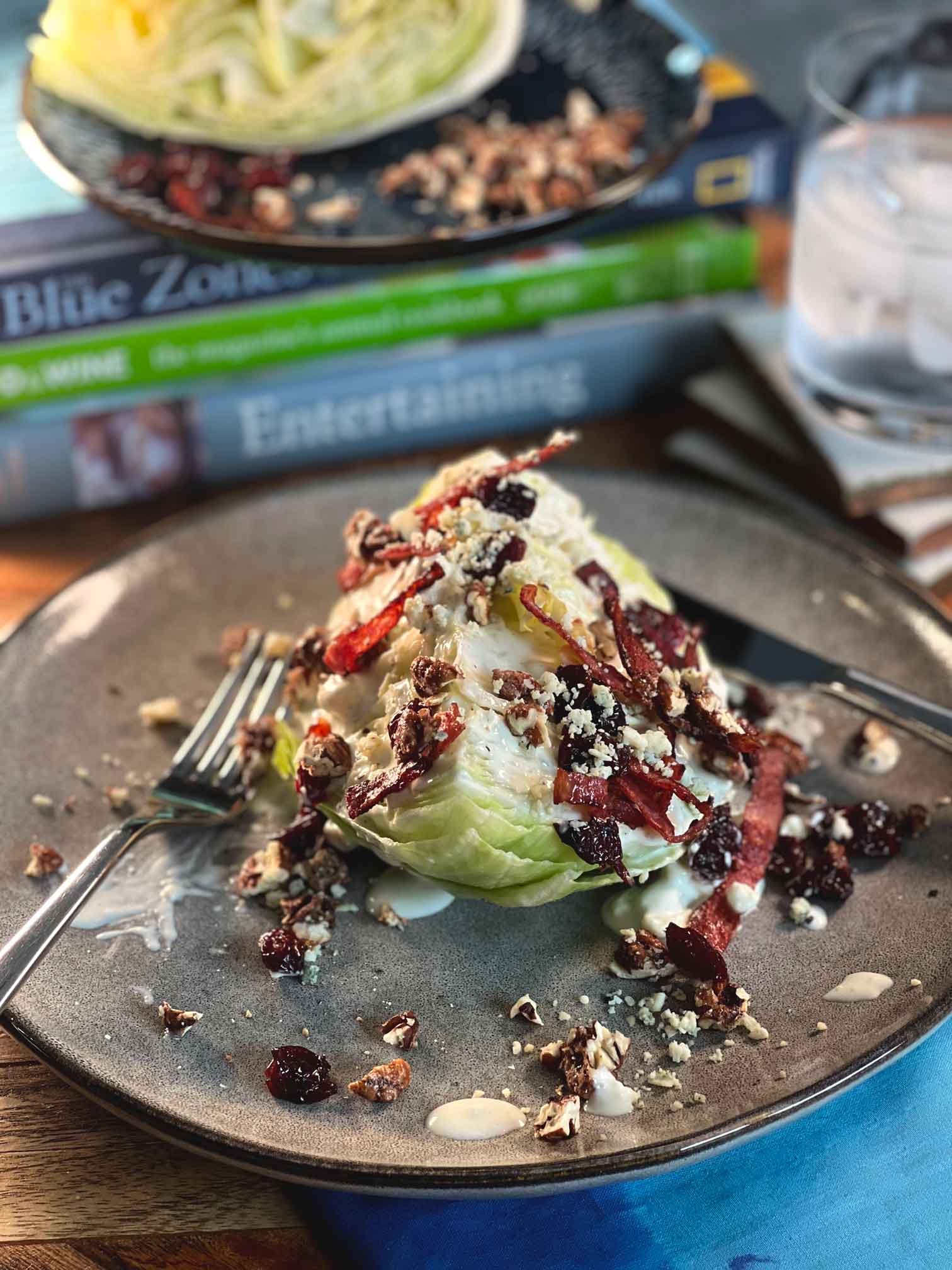 Wedge salad arranged on plate with crispy salami, candied pecans, blue cheese and dressing.