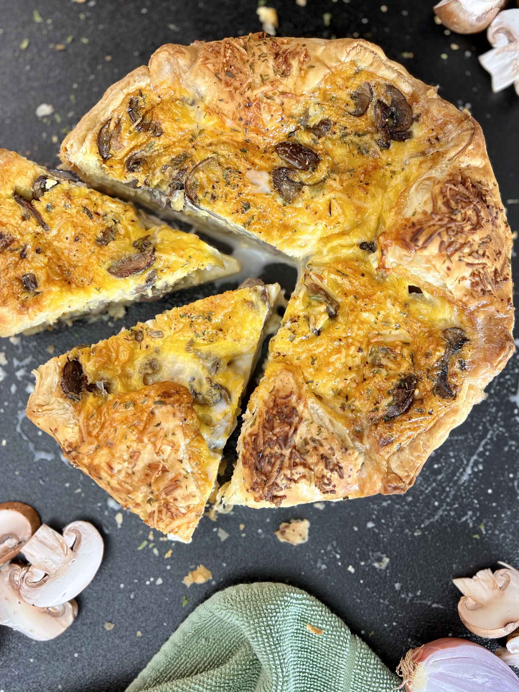 Five-cheese Mushroom Quiche cut with 2-slices arranged on surface with mushrooms