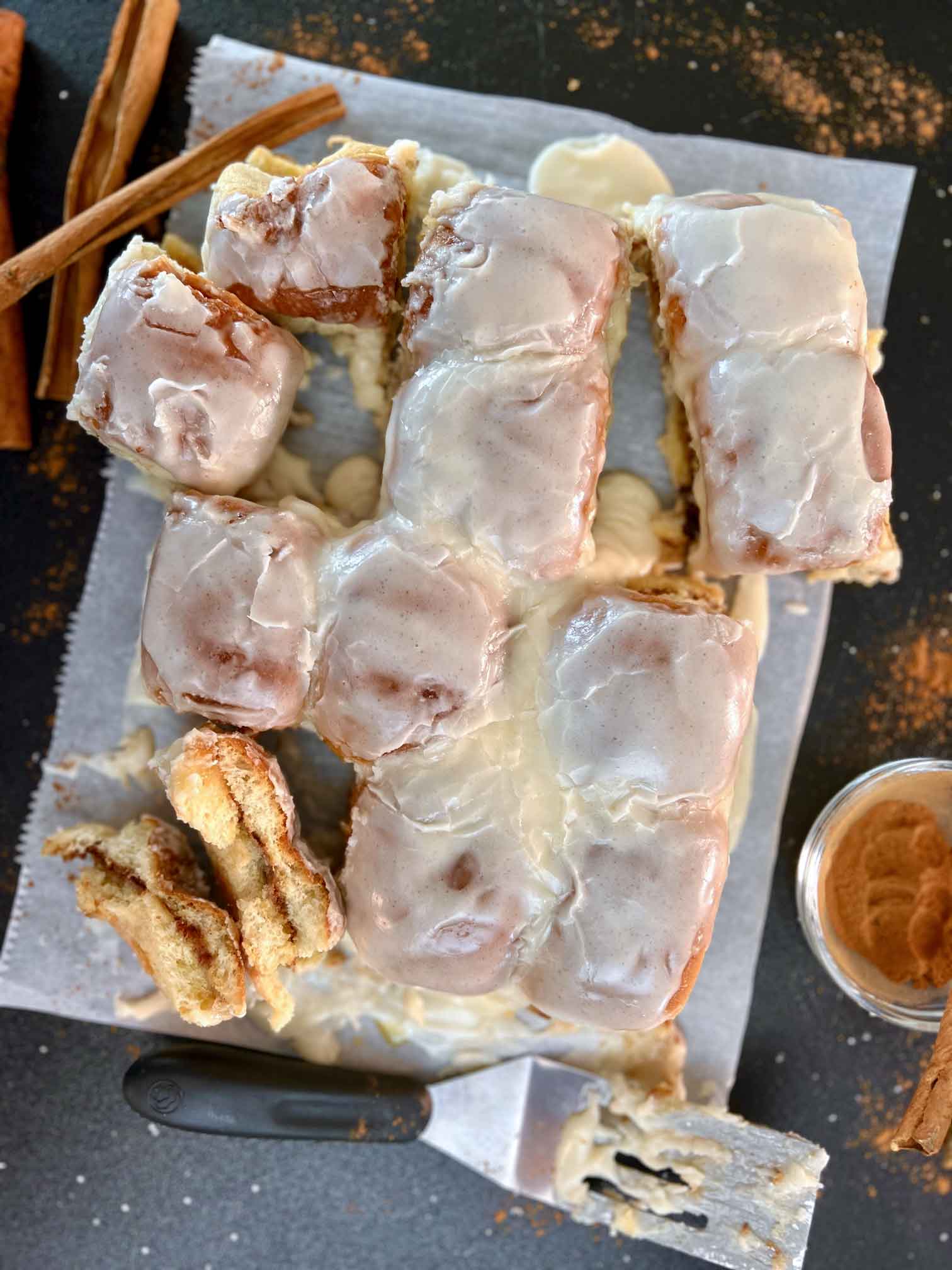 Hawaiian Cinnamon Sweet Rolls with Ground Cinnamon and sticks arranged on parchment paper